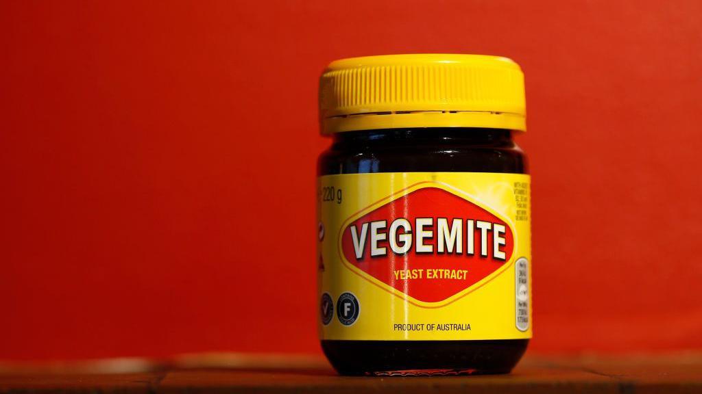 A yellow jar of Vegemite on a shelf